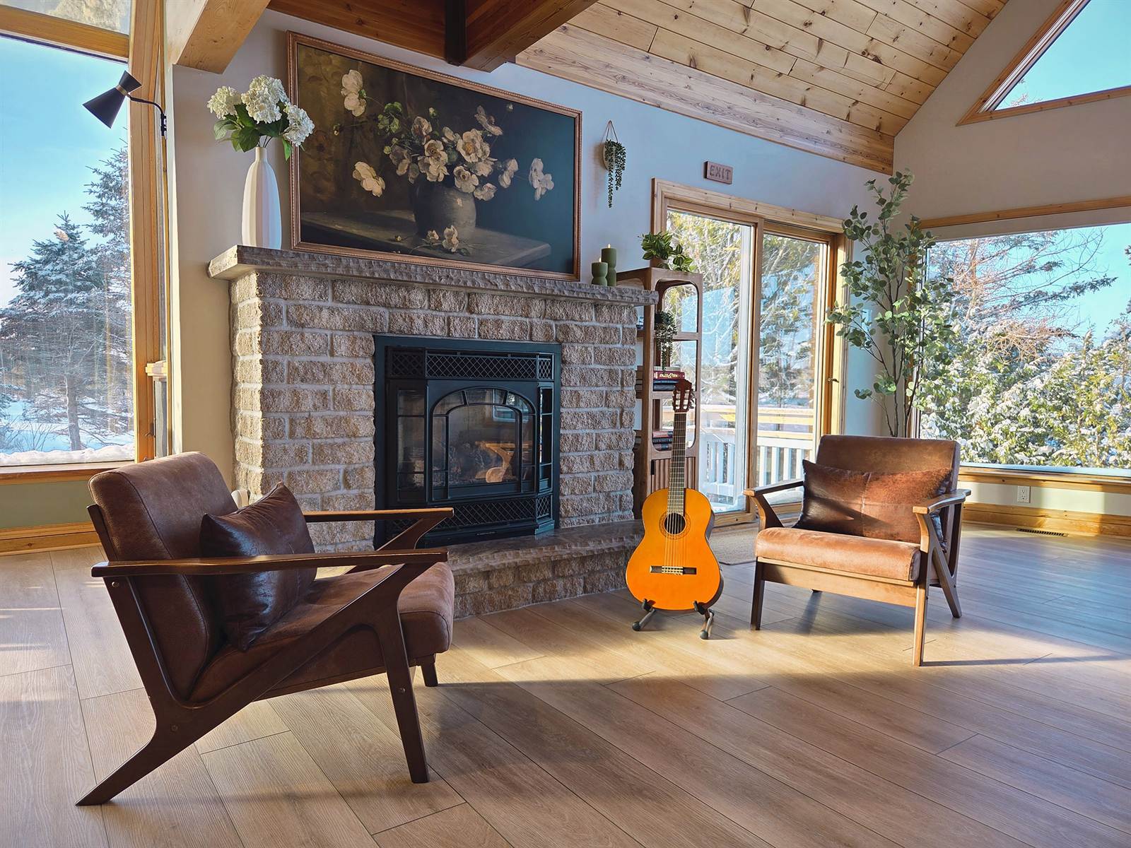 Stone fireplace with leather armchairs and a guitar, snowy windows behind