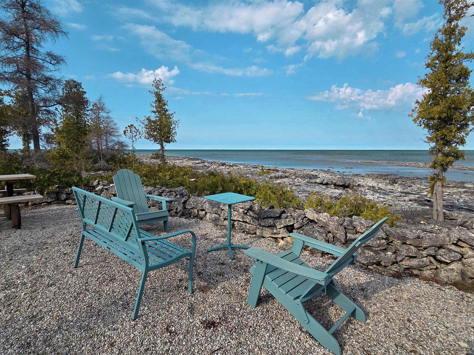 Adirondack chairs at the water's edge on the limestone shore