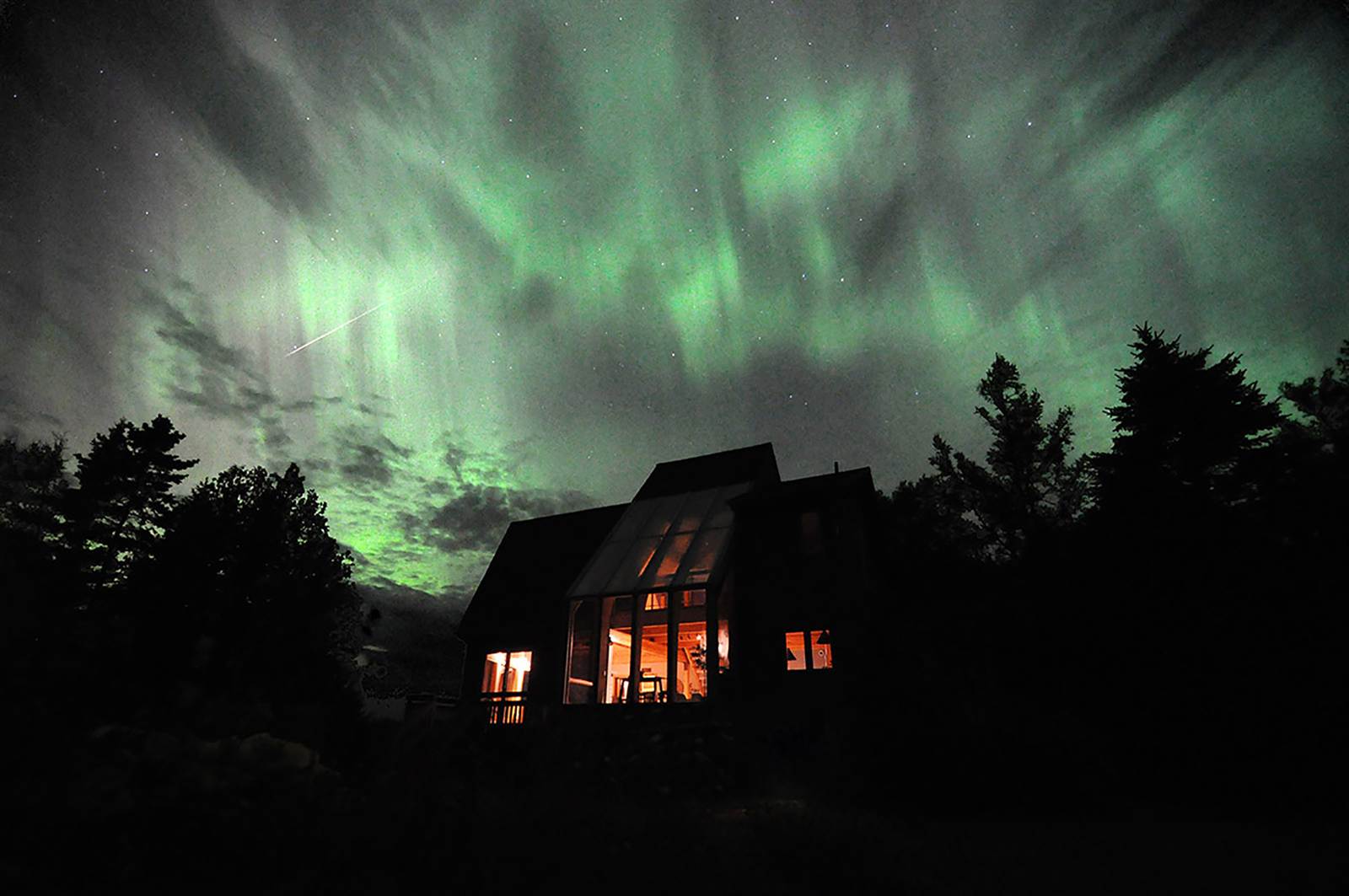 Northern lights and a shooting star over the cottage sunroom