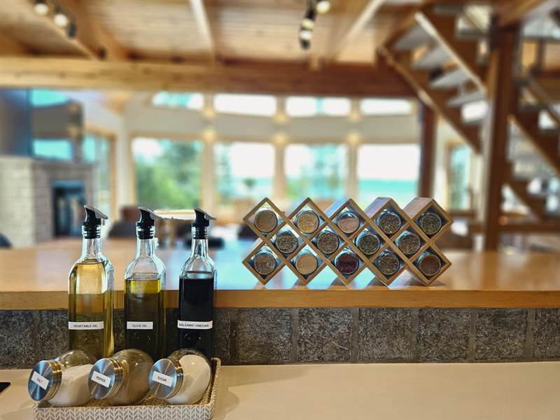 Labelled oil bottles, salt and pepper jars and a wooden spice rack on the kitchen counter