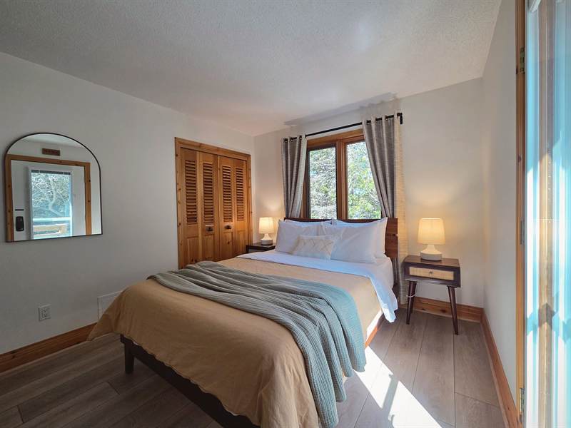 Bedroom with queen bed, louvered pine closet doors, arched mirror and bedside lamps
