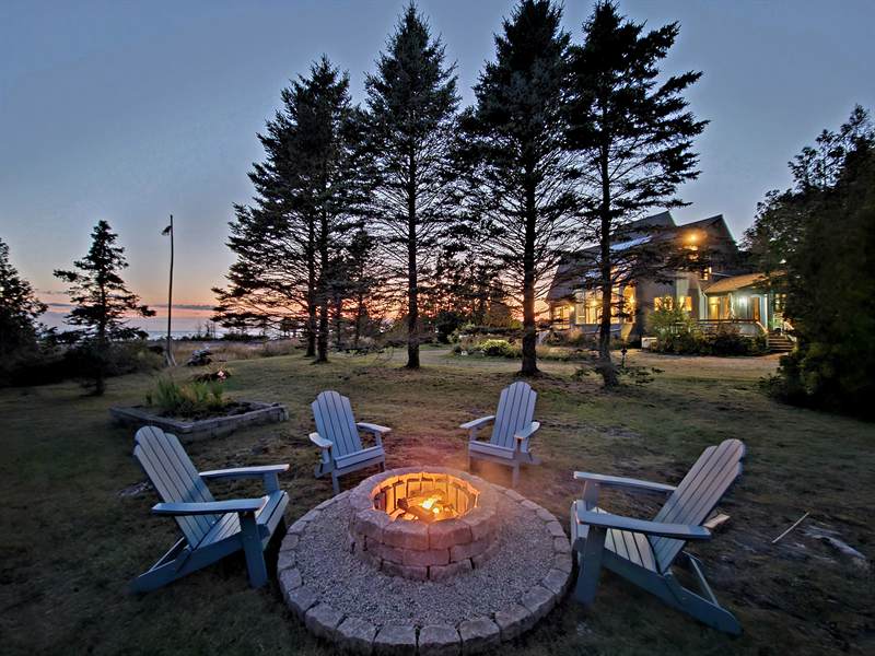 Fire pit at dusk with the lit cottage behind